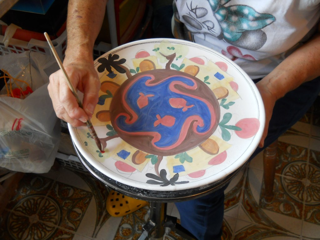 In questa foto sto dipingendo un piatto con la decorazione Naif Mediterranea